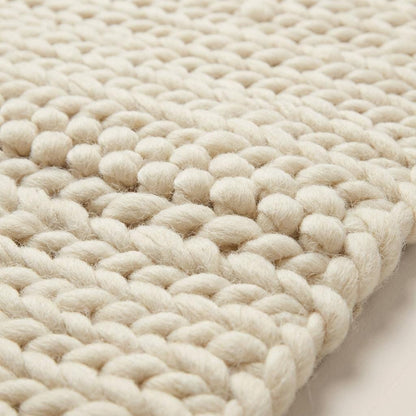 Chunky knit area rug with thick, textured neutral yarn, adding cozy warmth and modern organic style to floors