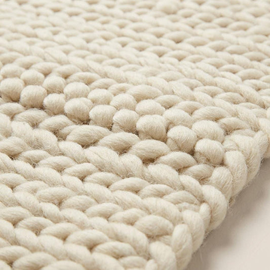 Chunky knit area rug with thick, textured neutral yarn, adding cozy warmth and modern organic style to floors