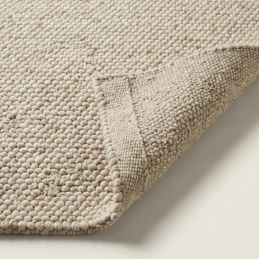 Thick chunky knit area rug with looped wool texture in neutral tones for cozy living room and bedroom decor