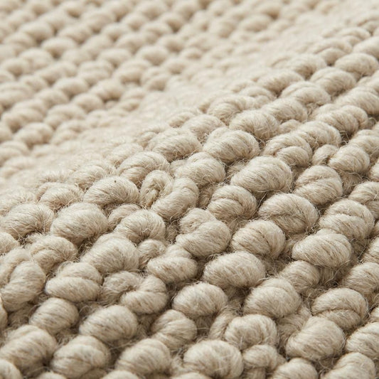 Chunky knit neutral rug with thick oversized loops and warm textured natural fibers for cozy Scandinavian interiors