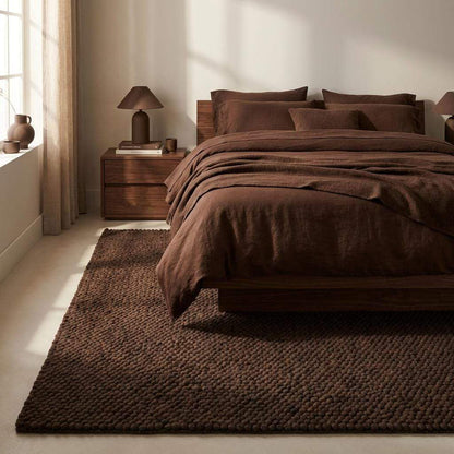 Chunky knit rug in dark brown with thick braided roving texture for cozy modern organic interiors