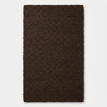 Chunky knit rug in dark brown with thick braided roving texture for cozy modern organic interiors