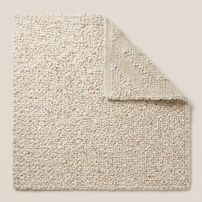 Handwoven chunky knit wool rug in ivory with thick loop texture for cozy, minimalist living room decor