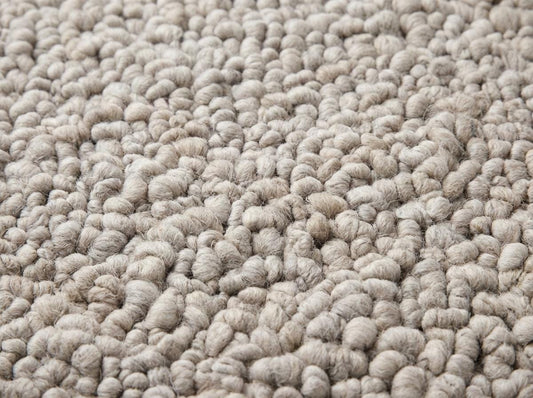 Handmade chunky knit wool rug in neutral beige with thick pebble texture for cozy modern minimalist decor