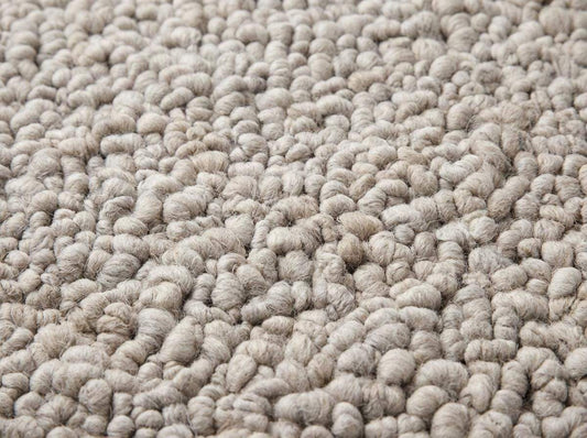 Handmade chunky knit wool rug in neutral beige with thick pebble texture for cozy modern minimalist decor