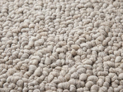 Handmade chunky knit wool rug in neutral beige with thick pebble texture for cozy modern minimalist decor