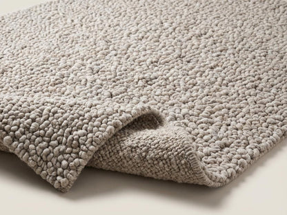 Handmade chunky knit wool rug in neutral beige with pebble texture, thick and cozy for modern minimalist decor