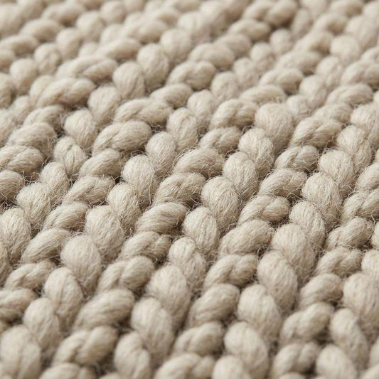 Chunky knit wool rug in neutral cream with thick, plush texture for cozy living room decor