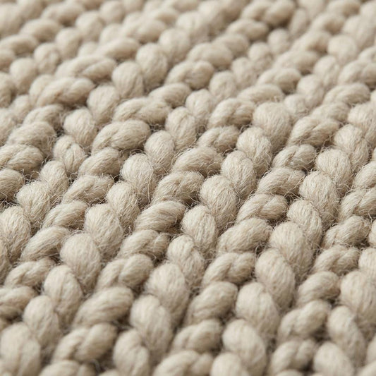 Chunky knit wool rug in neutral cream with thick, plush texture for cozy living room decor