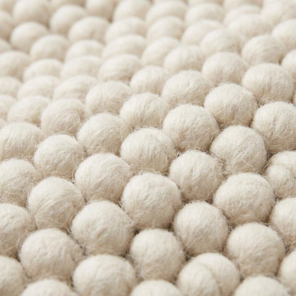 Handmade chunky knit wool rug with thick looped texture in neutral ivory, cozy Scandinavian minimalist floor design