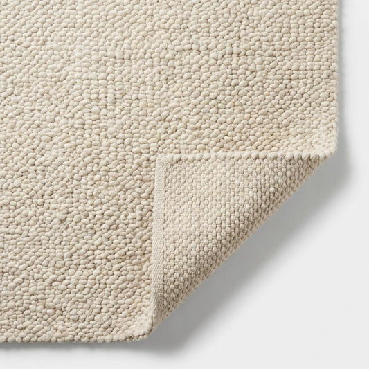 Detailed view of rug edge showing thick handwoven loops and durable wool construction, highlighting chunky knit craftsmanship and premium finish