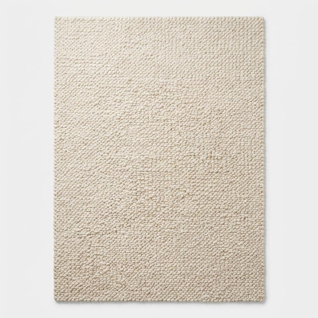 Handmade chunky knit wool rug in ivory with thick textured loops, cozy minimalist Scandinavian design for living rooms and nurseries