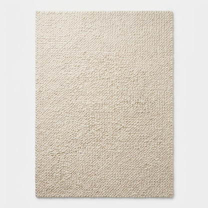 Handmade chunky knit wool rug in ivory with thick textured loops, cozy minimalist Scandinavian design for living rooms and nurseries