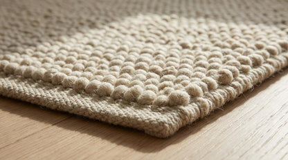 Chunky knit wool rug in cream beige with thick handmade textured loops creating a cozy, plush area rug