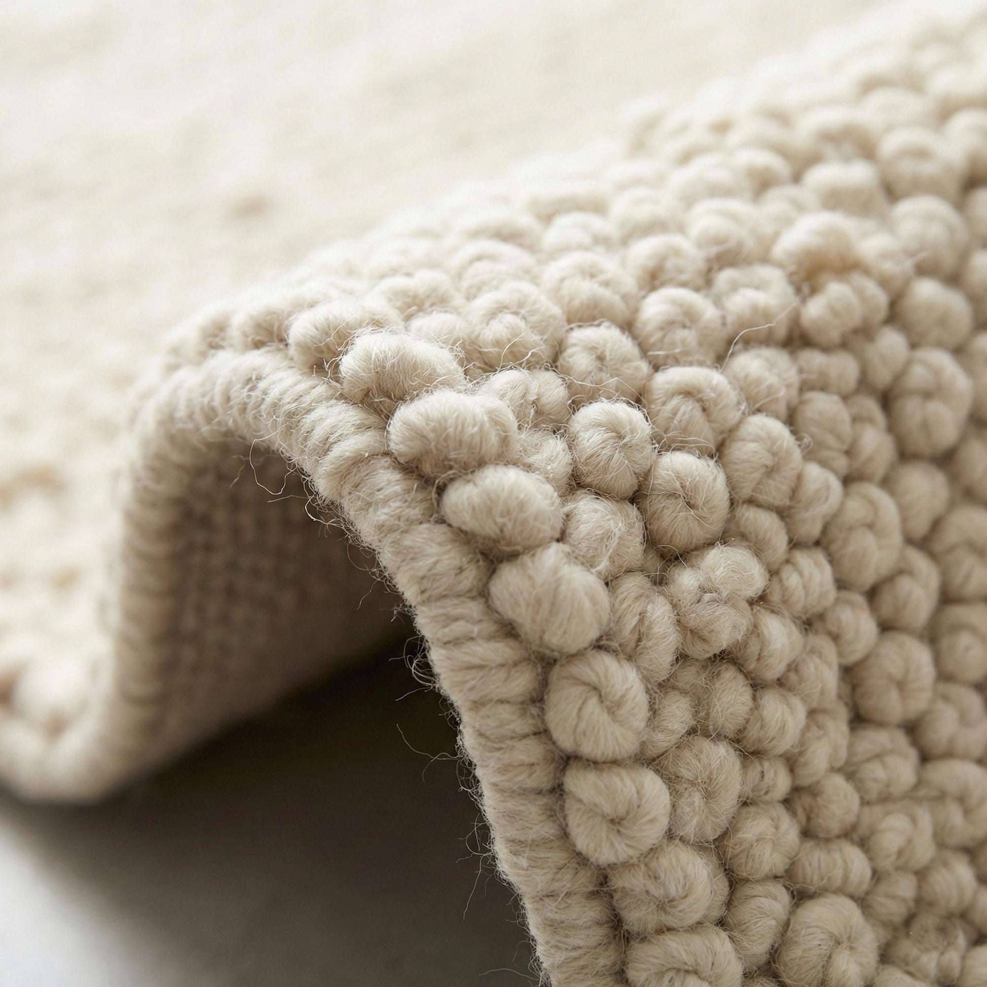 Ivory chunky knit wool rug with thick braided texture and soft hand-knit fibers for cozy neutral decor