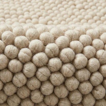 Chunky knit wool rug in ivory with thick braided texture and soft natural fibers for cozy neutral decor