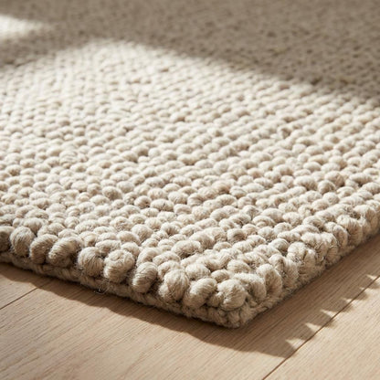 Detailed edge view of dense loop construction in textured beige rug