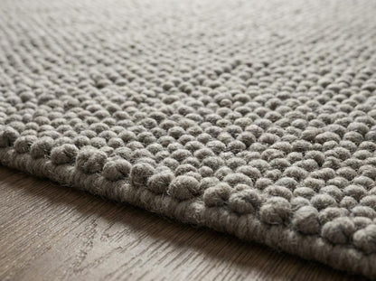 Chunky loop textured neutral rug with thick yarn loops in cozy Scandinavian minimalist living room