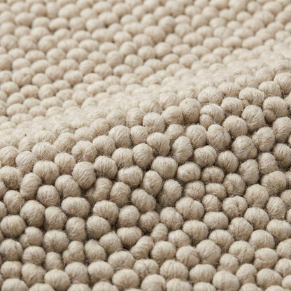 Chunky loop textured neutral area rug with braided edges in a modern organic interior setting