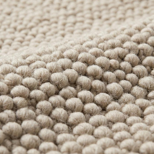 Cream minimalist textured rug surface highlighting dense looped yarn pattern