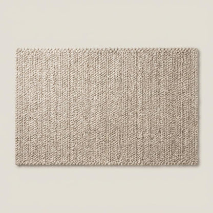 Folded neutral area rug revealing woven backing and thick textured edge