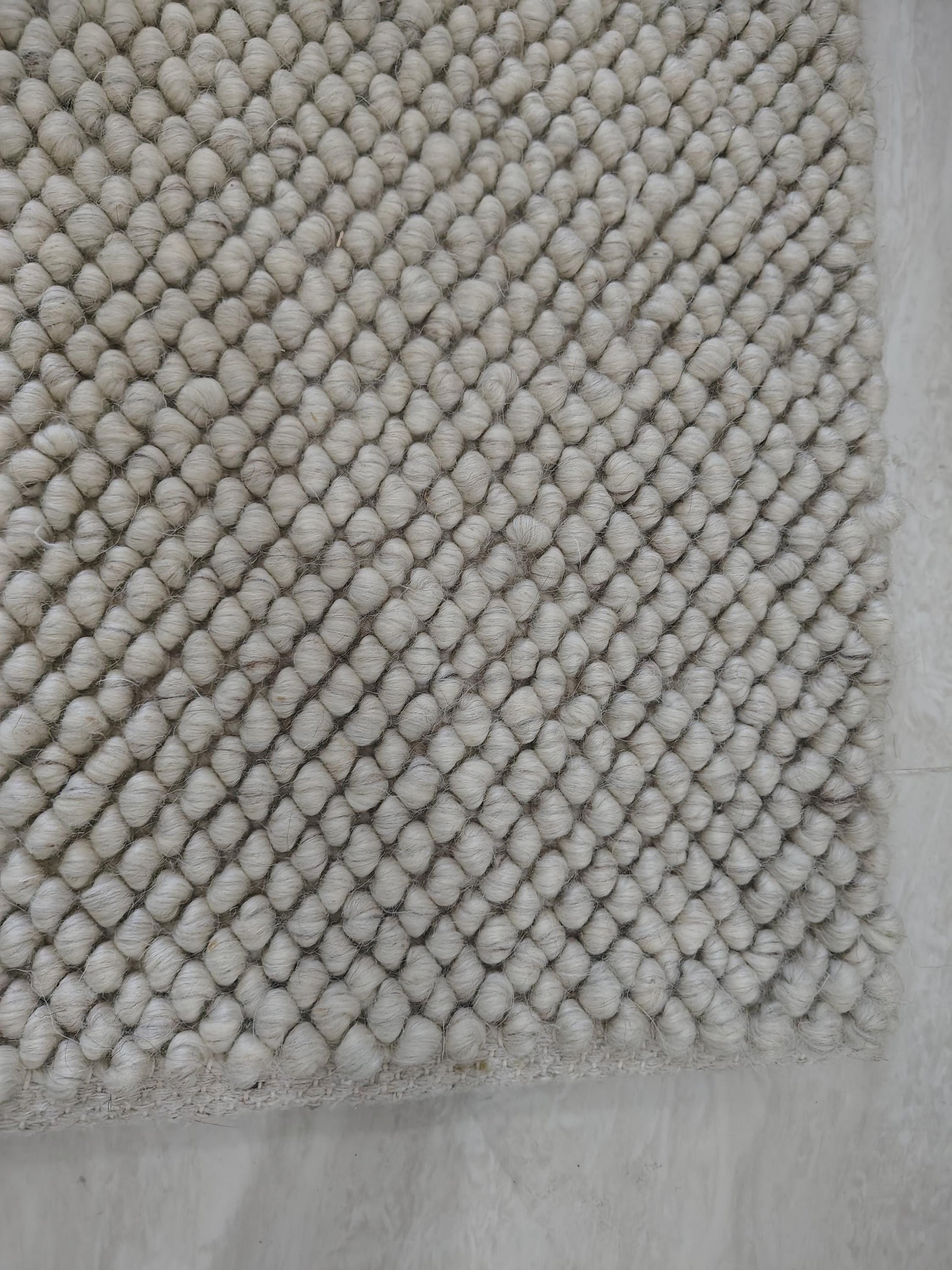 Detailed texture view of dense cream loop rug with sculpted surface