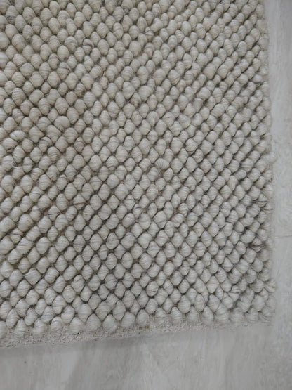 Detailed texture view of dense cream loop rug with sculpted surface