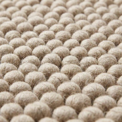Close-up of thick pebble-textured neutral rug showing dense yarn clusters