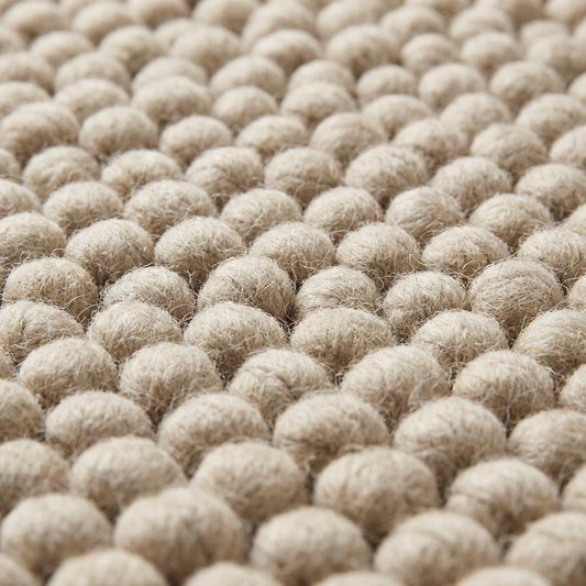 Close-up of thick pebble-textured neutral rug showing dense yarn clusters