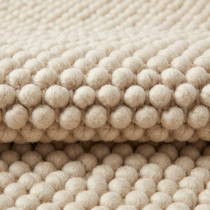 Chunky textured neutral area rug with thick looped plush surface in cozy living room setting