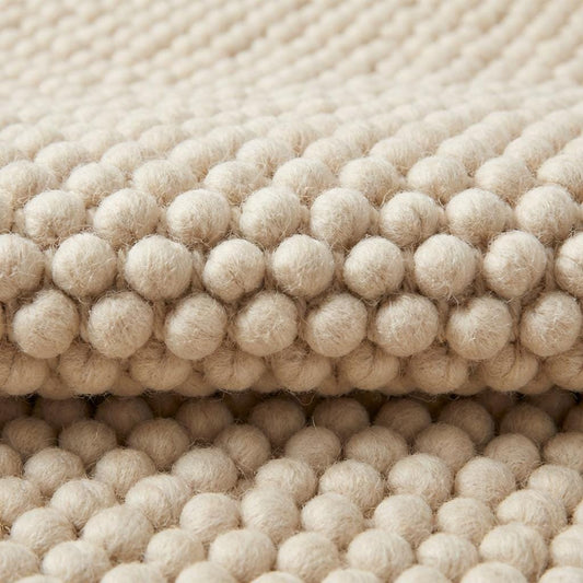 Chunky textured neutral area rug with thick looped plush surface in cozy living room setting