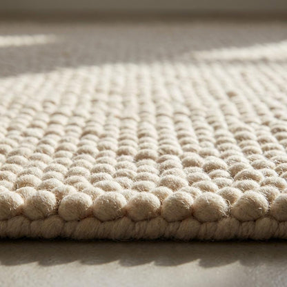 Chunky textured neutral area rug with thick looped plush surface in cozy living room setting
