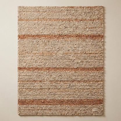 Top-down view of dense chunky wool rug with cream and rust toned striping