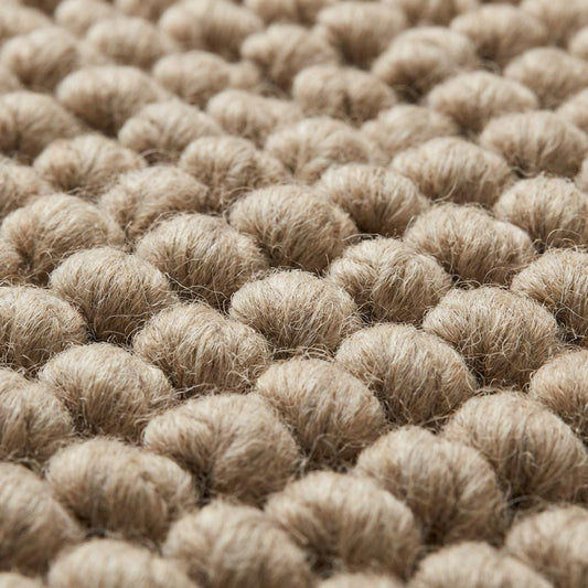 Chunky wool area rug with thick, braided neutral beige texture in living room.