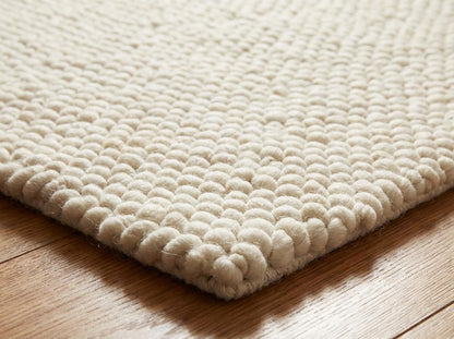 Chunky wool ivory area rug with thick textured loops in Scandinavian neutral living room setting