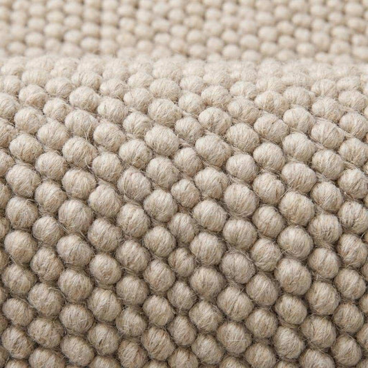 Close view of oversized loop texture rug showing thick natural yarn structure