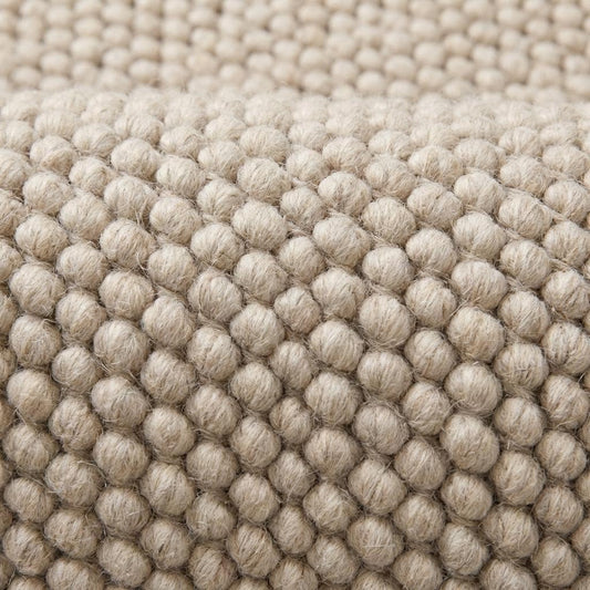 Close view of oversized loop texture rug showing thick natural yarn structure