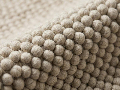 Close-up detail of thick oversized wool loops showing pebble-like texture