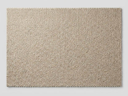 Top-down view of textured neutral wool rug with dense handcrafted surface