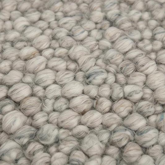 Handmade natural wool rug with thick pebble texture, beige and ivory fibers, ideal for modern minimalist living room décor.
