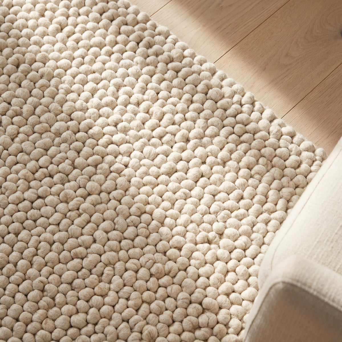 Handmade chunky wool pom pom rug in neutral tones, soft textured area rug for cozy boho nursery and living room decor