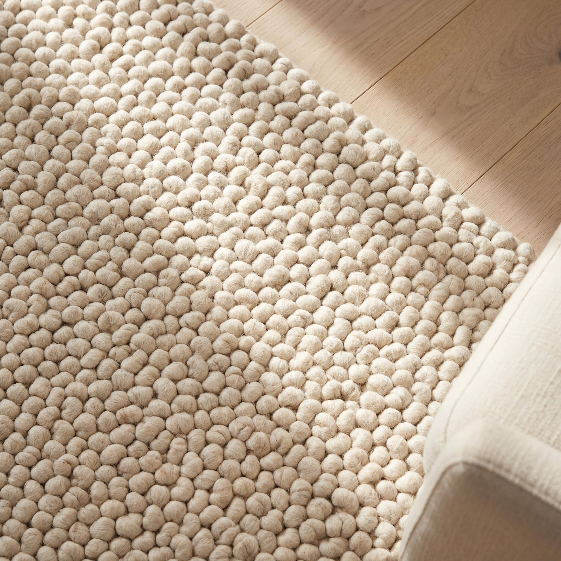 Handmade chunky wool pom pom rug in neutral tones, soft textured area rug for cozy boho nursery and living room decor
