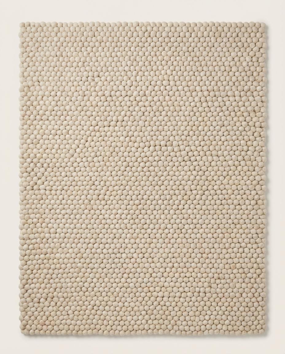 Handmade chunky wool pom pom rug in neutral tones, soft textured area carpet for cozy nursery and boho decor