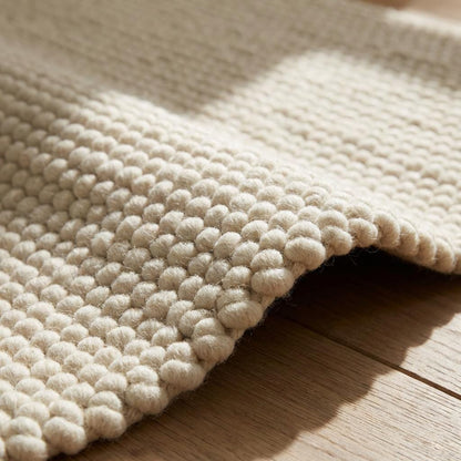 Chunky wool rug with handwoven pebble texture in neutral cream for modern boho minimalist decor
