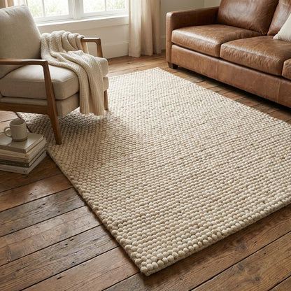 Textured cream wool floor rug with chunky woven design styled on hardwood floor for warm neutral decor aesthetic.