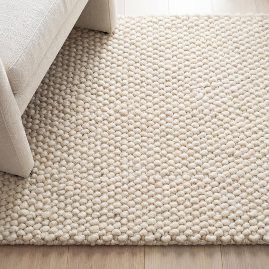 Chunky wool rug with neutral tones and soft loop pile texture in minimalist living room