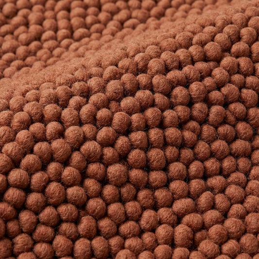 Chunky wool rug in warm rust tone with plush looped texture for cozy living room or bedroom decor
