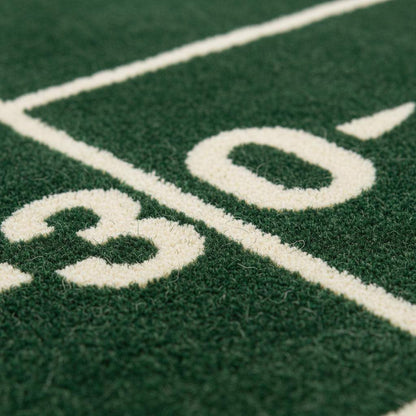 Close-up of plush green rug showing dense cut pile texture, clean white yard lines, and smooth fiber finish.