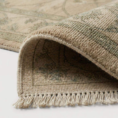 Close-up of the hand-knotted wool fibers showing the intricate knot structure, natural wool texture, and subtle sage green and tan yarn variations.