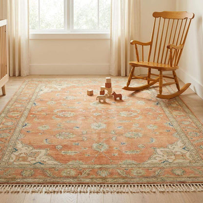 Wide shot of a large terracotta Oushak rug as the centerpiece of a sophisticated living room with natural lighting.